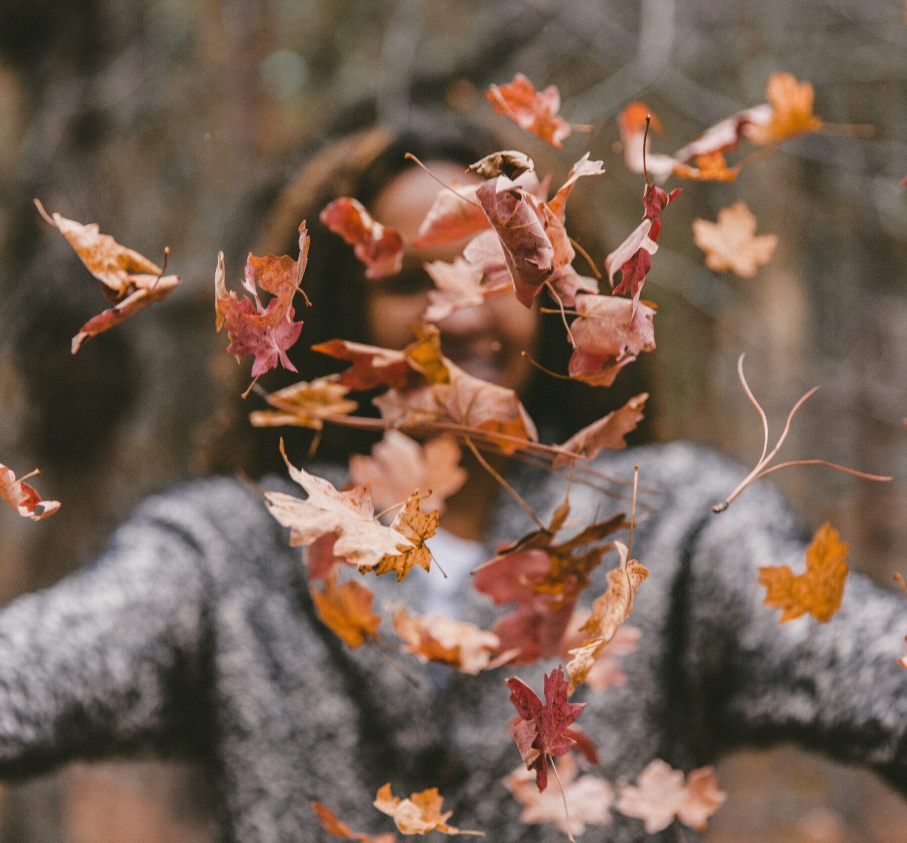 happy person throwing fall leaves in air