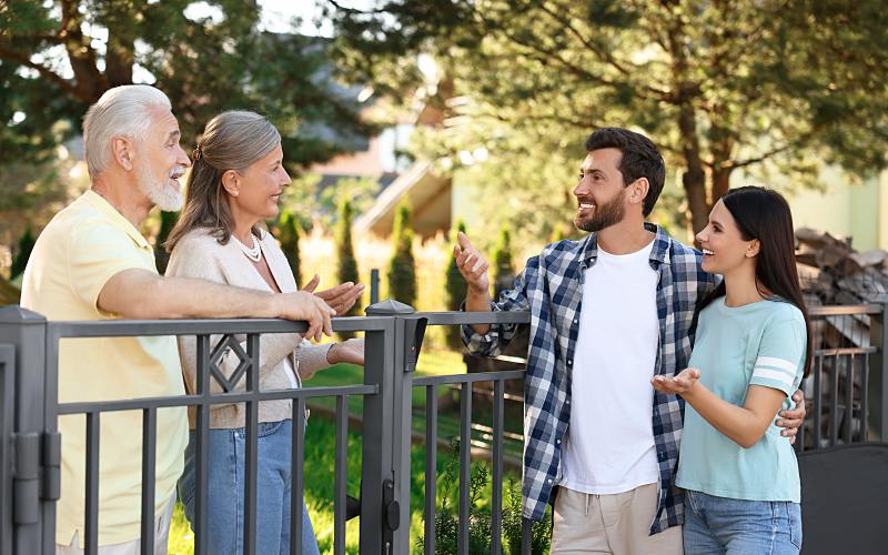 two neighbors talking by a fence