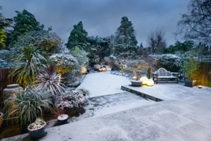 beautiful english designer garden and patio with garden lighting in snow