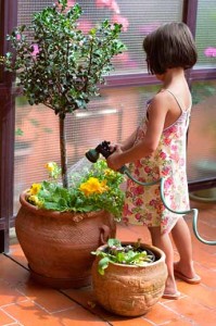 Little girl watering the plants on the terrace