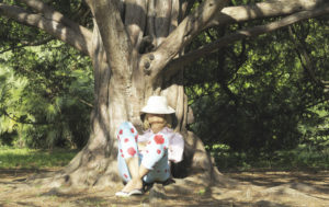 Little girl sitting on exposed tree roots